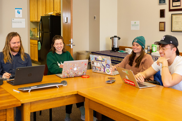 4 students in collaboration smiles at the Ostrom Workshop.