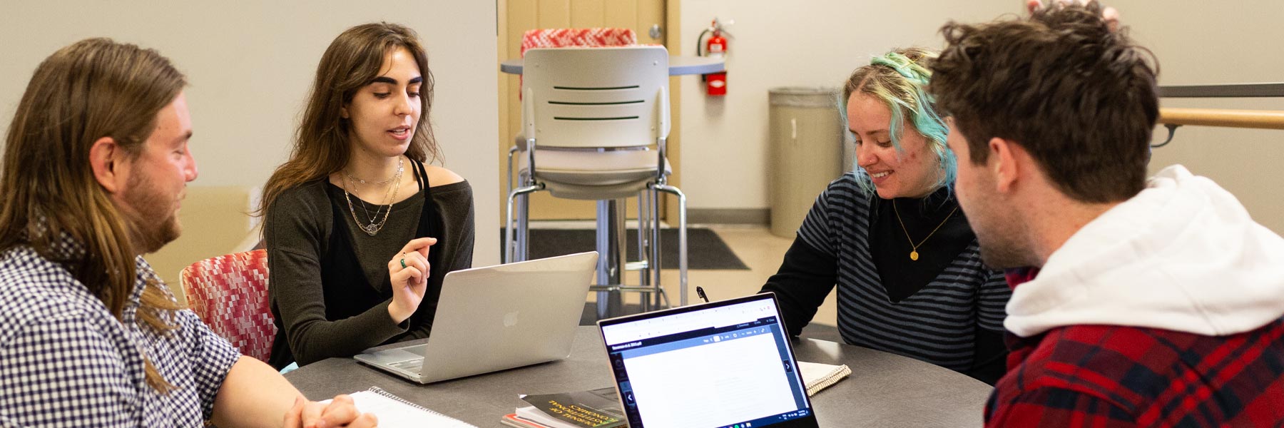 Four students collaborate together over laptops in the Ostrom Workshop. 